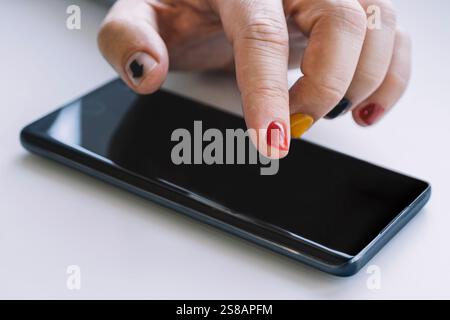 Gros plan d'un homme utilisant un smartphone mobile. La flèche sur l'ongle pointe vers l'écran du smartphone. Un homme avec une manucure touche sur l'écran du smartphone Banque D'Images