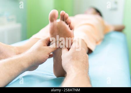 Femme recevant un massage des pieds au spa de santé. Concept de massages spa. Un masseur masculin professionnel pétrit le pied d'une jeune femme. Banque D'Images