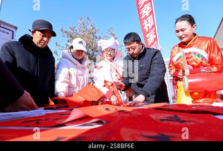 Zhangye, Chine. 22 janvier 2025. Les fans du patrimoine culturel immatériel écrivent des couplets du Festival de printemps pour les touristes sur la place culturelle du village de Zhenjiang dans la ville de Heiquan, comté de Gaotai, ville de Zhangye, province du Gansu du Nord-Ouest de la Chine, le 21 janvier 2025. (Photo de Costfoto/NurPhoto) crédit : NurPhoto SRL/Alamy Live News Banque D'Images