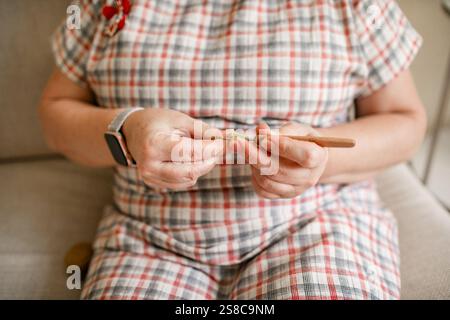 Vue rapprochée des mains d'une femme âgée crochetant. Banque D'Images