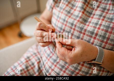 Vue rapprochée des mains d'une femme âgée crochetant. Banque D'Images
