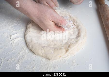 Les mains d'un homme et d'un enfant en farine font une tarte ou une pizza à partir de pâte. Le concept de relations familiales, de soutien et d'amour. Passer du temps ensemble Banque D'Images