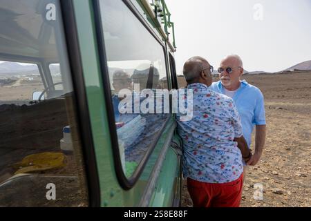 Un couple senior gay partage un moment tendre tout en campant dans une région éloignée avec leur véhicule hors route. Les deux hommes sont engagés dans une douce étreinte, looki Banque D'Images
