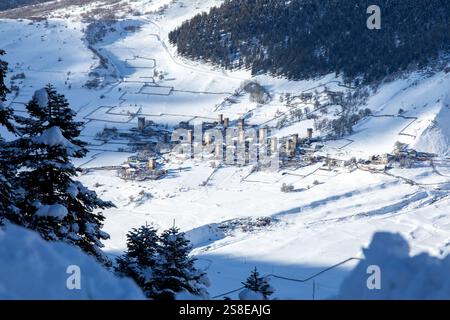 Un village pittoresque niché dans une vallée enneigée, avec d'anciennes tours de guet au milieu d'un paysage hivernal immaculé dans les arbres de Géorgie encadrent la scen Banque D'Images