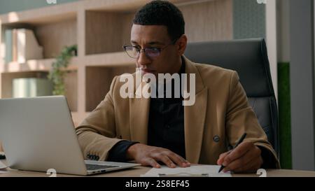 Homme afro-américain comptable homme homme homme homme homme analyste écrire des notes informations de données écrire des documents de rapport de projet de budget d'entreprise dans le bureau Banque D'Images
