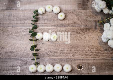 Un signe £ fait de têtes de fleurs vives blanches et d'eucalyptus se trouve à côté d'une pièce d'une livre, mélangeant la nature avec la finance, la croissance durable, l'investissement Banque D'Images