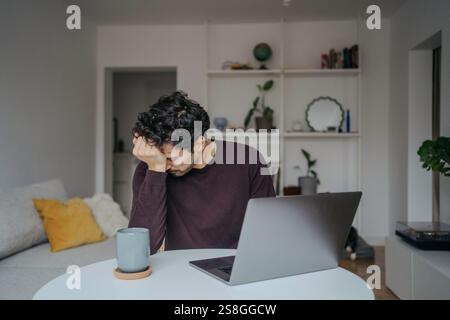Jeune stressé regardant bel homme du moyen-Orient utilisant l'ordinateur et étant submergé par le travail. Banque D'Images