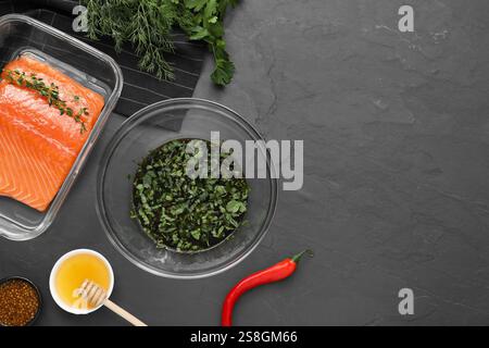 Marinade de soja dans un bol, filet de saumon et autres produits sur une table texturée gris foncé, pose à plat. Espace pour le texte Banque D'Images