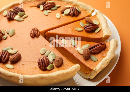 Savoureuse tarte à la citrouille maison avec des graines et des noix sur fond orange, gros plan Banque D'Images