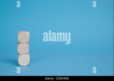 Trois blocs de bois sont empilés verticalement sur un fond bleu, laissant de l'espace à proximité pour le texte. Banque D'Images
