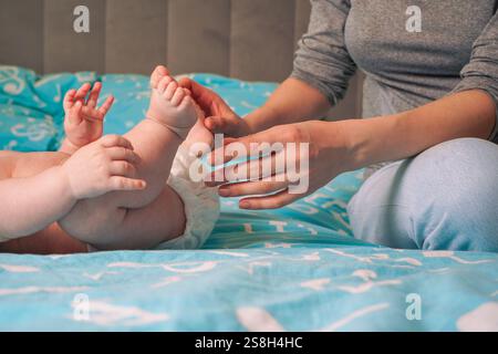 Pied de bébé entre les doigts de sa main mère. Gros plan. Concept de famille. Le petit pied d'un nouveau-né entre les doigts d'un parent Banque D'Images