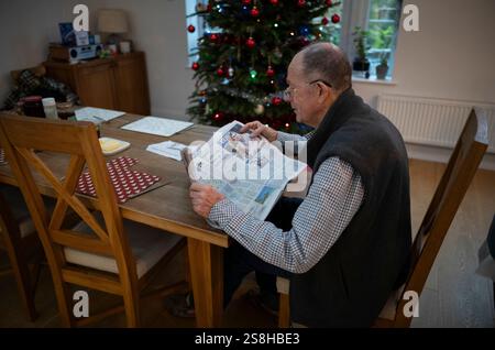 Homme âgé lisant un journal national britannique pendant la période de Noël, Londres, Angleterre, Royaume-Uni Banque D'Images