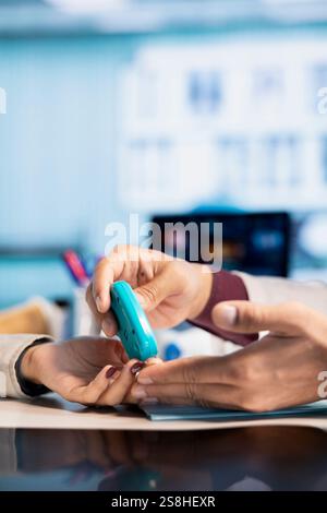 Contrôle de la glycémie des patients diabétiques par un professionnel de santé à l'aide d'outils diagnostiques. Médecin indien offre des conseils médicaux pour la gestion du contrôle de la glycémie, des soins d'expert dans le bureau moderne. Gros plan. Banque D'Images