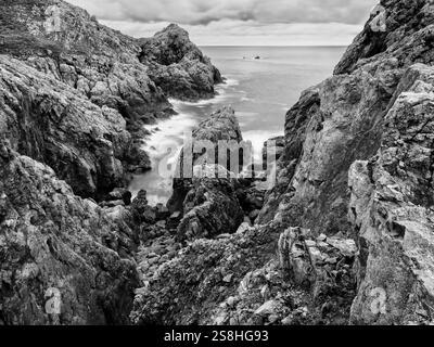 Falaises de mer de granit accidentées, avec une mer floue longue exposition, sur la côte sud de Guernesey, îles Anglo-Normandes. Banque D'Images