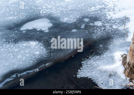 Lac partiellement gelé avec des motifs glacés à la surface formés par le gaz méthane émanant de bûches de bois pourries. Grotto Pond, Alberta, Canada. Banque D'Images