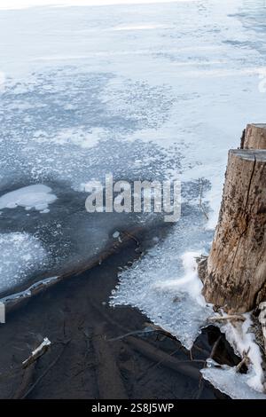 Lac partiellement gelé avec des motifs glacés à la surface formés par le gaz méthane émanant de bûches de bois pourries. Grotto Pond, Alberta, Canada. Banque D'Images