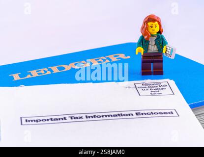 Chappaqua, NY - 11 avril 2024 : concept de jour de l'impôt sur le revenu Lego minifigure comptable avec livre de grand livre et enveloppe IRS qui dit information fiscale importante Banque D'Images