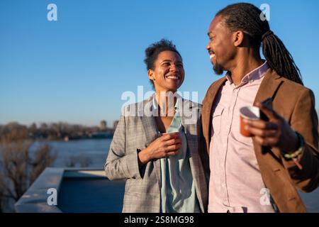 Un homme et une femme d'affaires joyeux habillé dans chic décontracté ayant une conversation sur le café en pause Banque D'Images