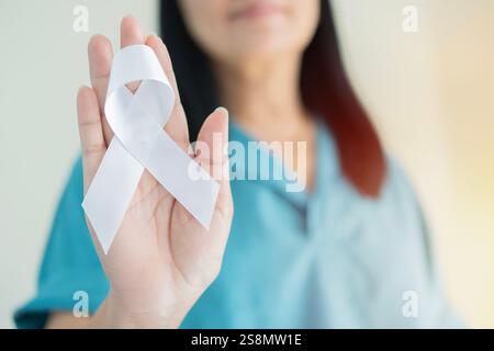Femme asiatique avec la conscience du ruban de perles blanches en main pour la violence de datation, emphysème, sensibilisation au cancer du poumon, maladie pulmonaire. Mise au point sélective. Banque D'Images