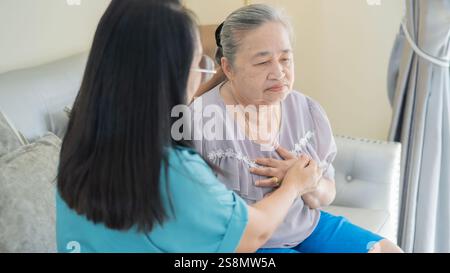 Problème respiratoire. Une femme plus âgée malade souffrant de douleurs thoraciques touchant la zone inflammée et une femme d'âge moyen ou une infirmière prennent soin d'elle. Banque D'Images