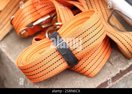 Sangles d'arrimage. Sangle de remorque en nylon orange et attache métallique. Gros plan d'une sangle de retenue de charge. Sangle d'arrimage de l'espace de chargement. Attache de chargement Banque D'Images