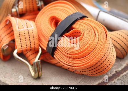 Sangles d'arrimage. Sangle de remorque en nylon orange et attache métallique. Gros plan d'une sangle de retenue de charge. Sangle d'arrimage de l'espace de chargement. Attache de chargement Banque D'Images