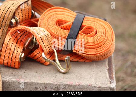 Sangles d'arrimage. Sangle de remorque en nylon orange et attache métallique. Gros plan d'une sangle de retenue de charge. Sangle d'arrimage de l'espace de chargement. Attache de chargement Banque D'Images