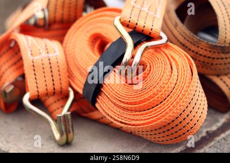 Sangles d'arrimage. Sangle de remorque en nylon orange et attache métallique. Gros plan d'une sangle de retenue de charge. Sangle d'arrimage de l'espace de chargement. Attache de chargement Banque D'Images
