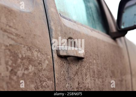 Poignée de porte de voiture dans la boue, gros plan. Camionnette dans la boue, éclaboussures de boue sur le côté de la camionnette. Voiture sale après avoir conduit sur un terrain marécageux. Porte ha Banque D'Images