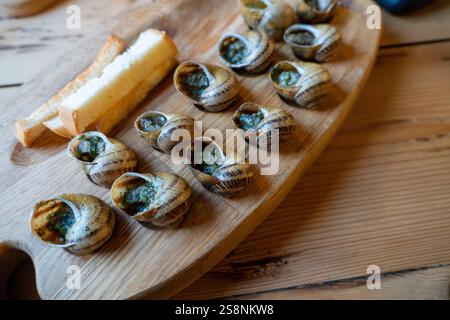 Escargot et pain sur plateau en bois : délicatesse culinaire française Banque D'Images