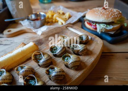 Délicieux escargot et cheeseburger avec des frites sur une table en bois Banque D'Images