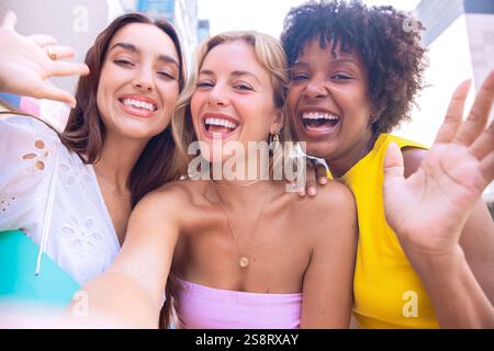 Trois jeunes femmes heureuses prenant un selfie ensemble dans une rue de la ville Banque D'Images