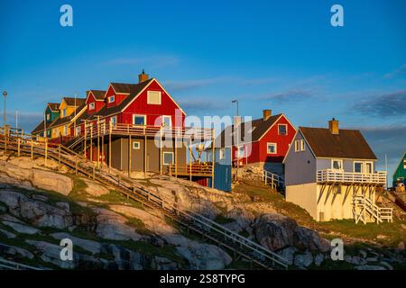 Des maisons aux couleurs vives parsèment la colline d'Ilulissat, au Groenland, se prélassant dans la chaude lumière estivale contre un ciel dégagé. Banque D'Images