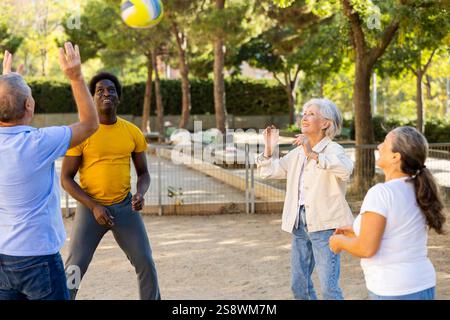 Club social de joyeux personnes âgées diverses appréciant le volley-ball le jour ensoleillé d'octobre plein air Banque D'Images