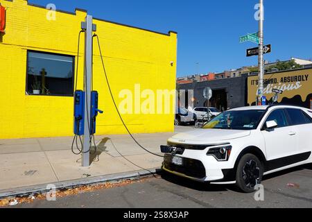 Un véhicule électrique branché sur un chargeur FLO EV à une borne de recharge PlugNYC située dans le quartier Greenpoint de Brooklyn, à New York. Banque D'Images