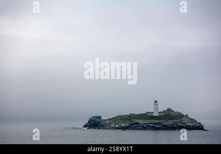 Le phare de Godrevy se dresse majestueusement à Godrevy point entouré de brouillard et de vagues océaniques à Cornwall, Angleterre, Royaume-Uni Banque D'Images
