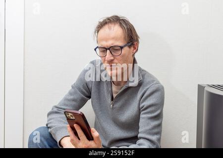 Professionnel réfléchi engagé avec un smartphone dans un cadre décontracté Banque D'Images