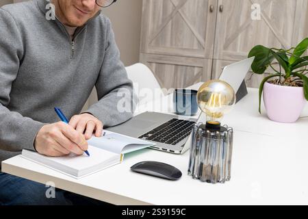 homme d'affaires souriant écrivant dans son livre dans son bureau à domicile Banque D'Images