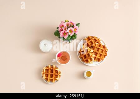 Gaufres et thé avec fleurs dans des tons beige doux Banque D'Images