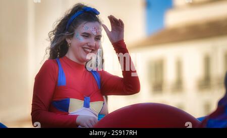 Individu costumé festif avec une expression joyeuse, saluant ludique à l'extérieur. La tenue colorée de maquillage pailleté suggère la célébration ou la performance Banque D'Images