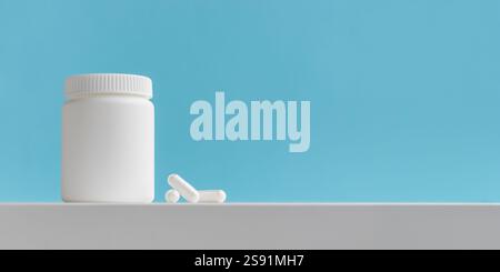 Pilules blanches et bouteille de médecine en plastique sur un fond bleu avec espace de copie. Les concepts de médecine et de santé incluent un pot avec des pilules ou des vitamines. Haut- Banque D'Images