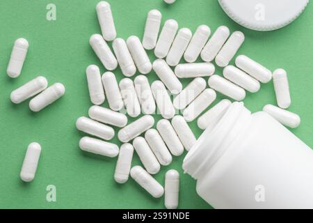 Médecine pharmaceutique et capsules avec la bouteille sur fond vert. Les concepts de médecine et de santé comprennent un pot avec des pilules, des antibiotiques ou des vitamines Banque D'Images