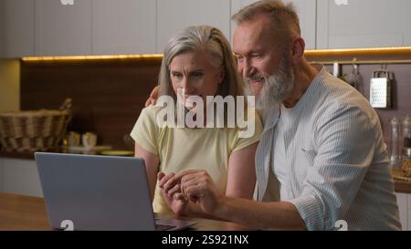 Famille heureuse vieux couple aîné utilisant un ordinateur portable commandant la livraison de nourriture dans le supermarché Internet e-commerce domestique femme moyenne de magasin en ligne d'épicerie Banque D'Images
