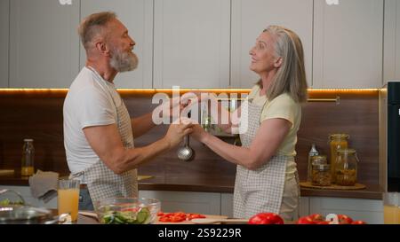 Caucasien couple d'amour heureux retraité famille vieil homme mature et femme cuisinant dans la cuisine à la maison danse romantique grand-mère grand-père célébrant Banque D'Images