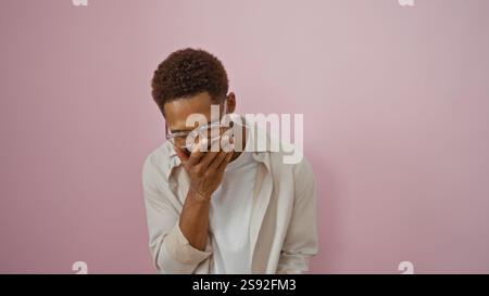 Beau jeune homme afro-américain riant avec la main sur la bouche sur un fond rose isolé Banque D'Images