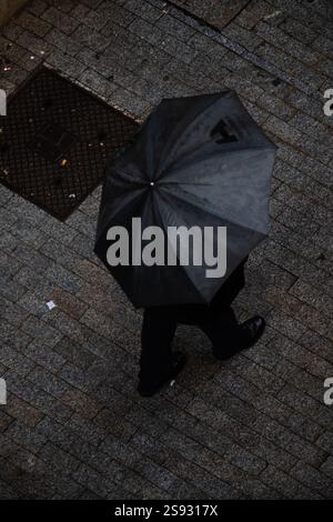 Vue d'en haut des personnes avec des parasols dans la rue un jour de pluie. Banque D'Images