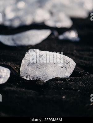 Gros plan de fragments de glace étincelants sur le sable noir de Diamond Beach (Breidamerkursandur), dans le sud de l'Islande. Banque D'Images