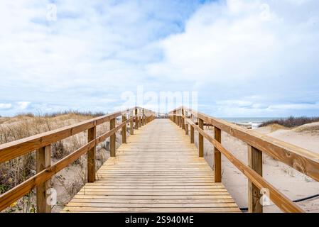 Promenade en bois invitante s'étendant vers une vue nuageuse sur la plage Banque D'Images