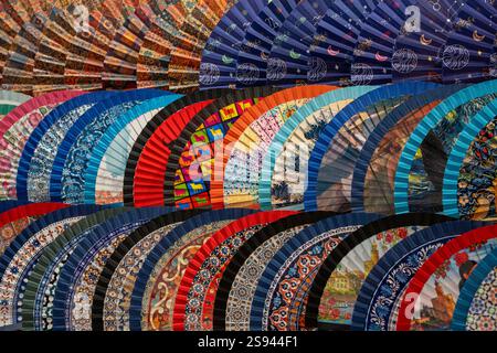 Une collection vibrante de fans espagnols traditionnels avec des motifs colorés et des motifs complexes exposés dans un marché de Séville, en Espagne. Parfait pour sh Banque D'Images
