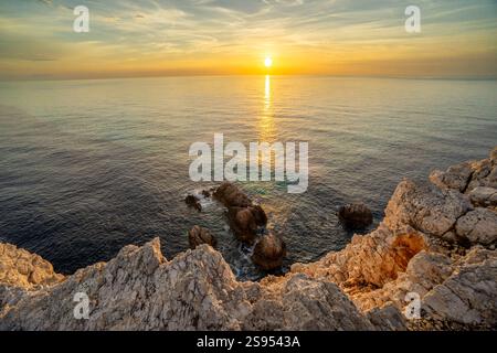 Coucher de soleil sur la mer calme et la côte rocheuse Banque D'Images